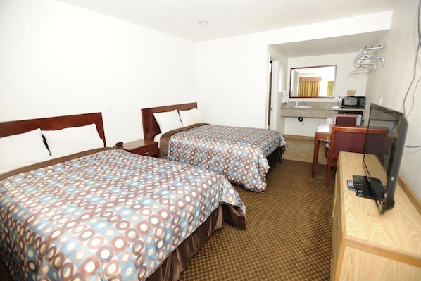 A hotel room with two beds, a desk with a computer, a mirror, and a bathroom visible through an open door. - Victoria Motel (Ventura)