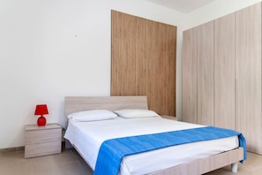 Une chambre à coucher avec un lit, une table de chevet, une lampe rouge et un mur recouvert de panneaux en bois.