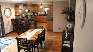 Una cocina con armarios de madera, una mesa de comedor con sillas y un reloj en la pared.