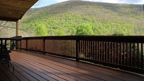 Una terraza de madera con barandilla, con vistas a una ladera boscosa.