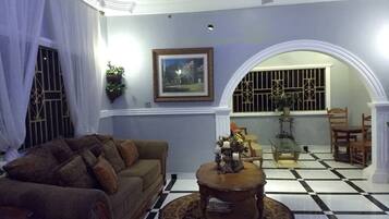A living room with a checkered floor, a sofa, a coffee table, and a ceiling fan.