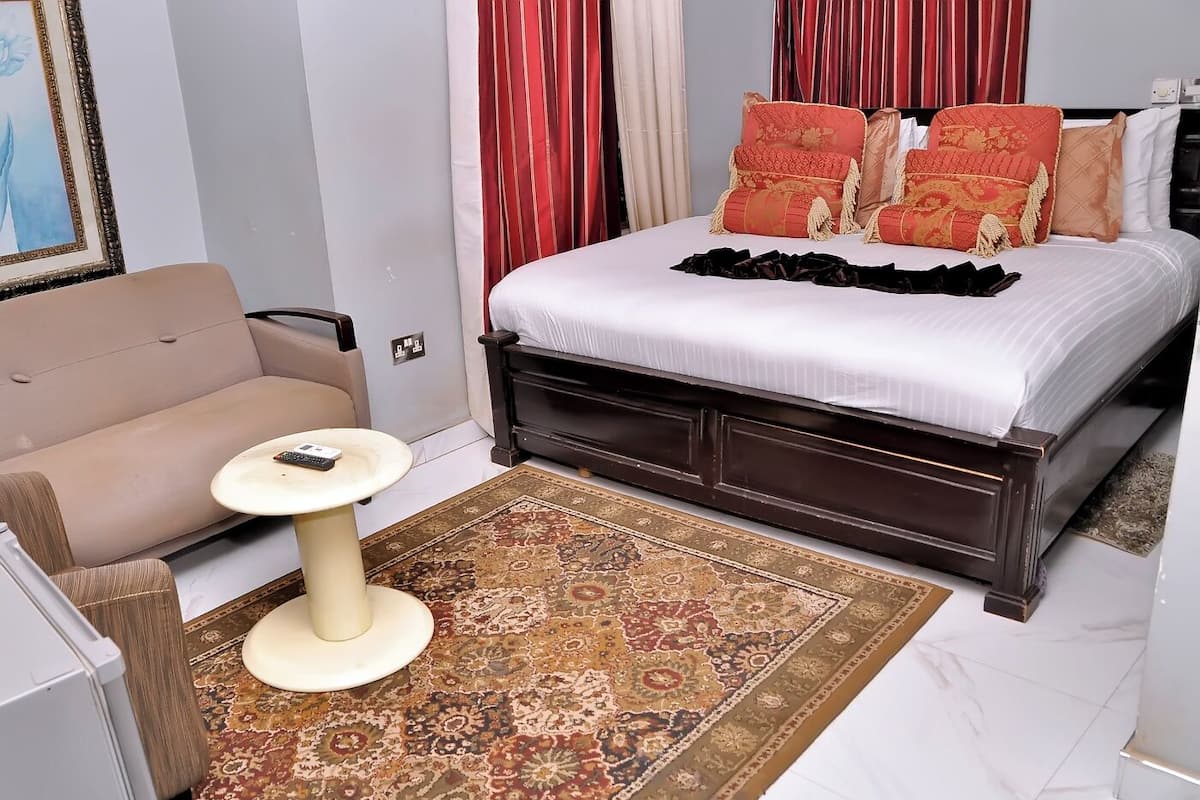 Een slaapkamer met een bed, een bank, een klein tafeltje en een kamerkleed met patroon.