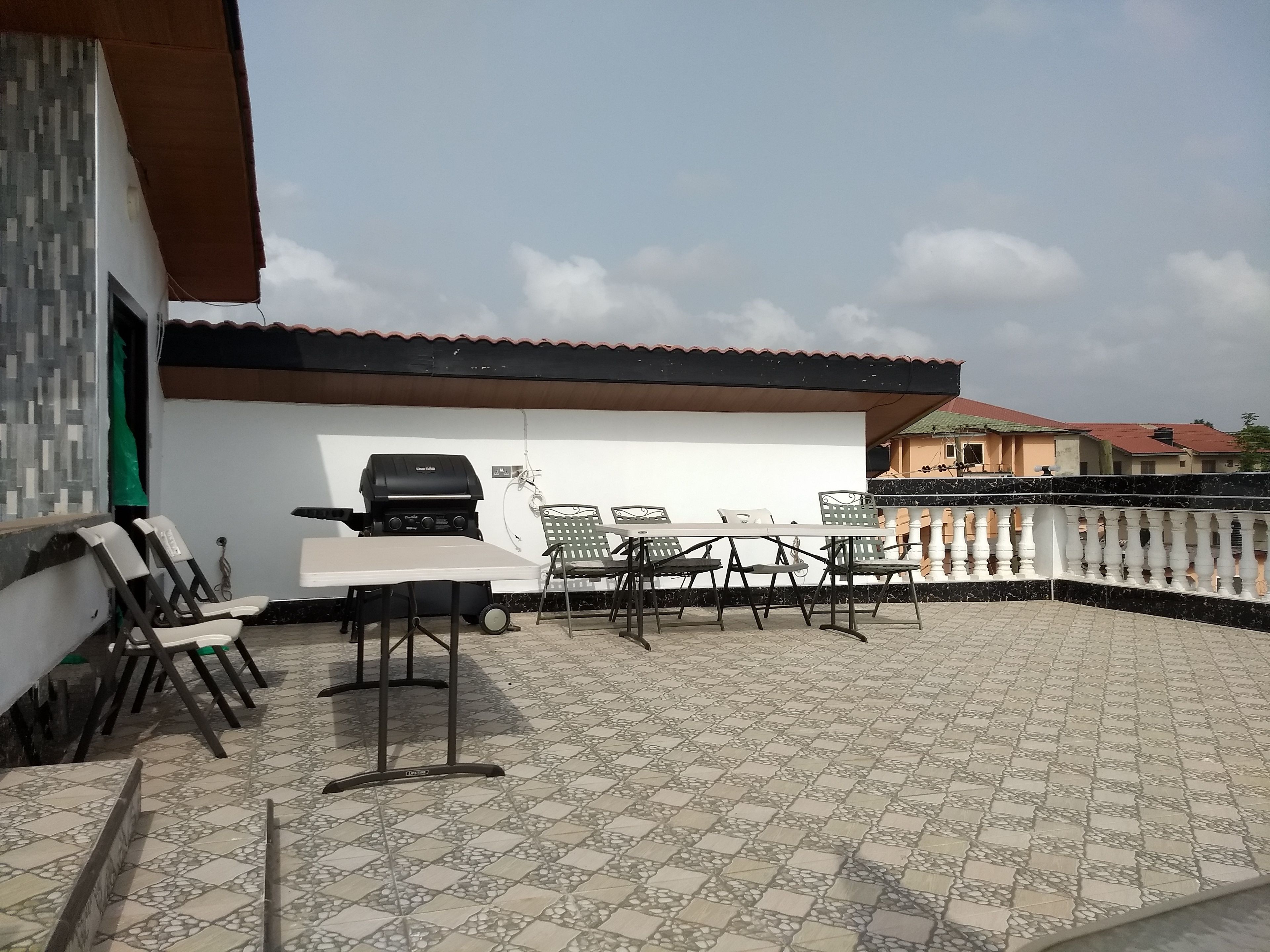 An outdoor patio with a grill, a table, and chairs.