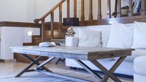 Un salon moderne avec un escalier en bois, un canapé blanc et une table basse.