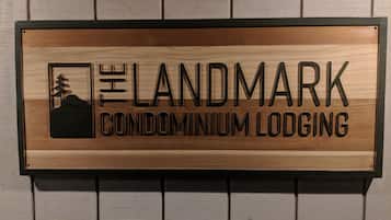 Et træskilt for Landmark Condominium Lodging med et bjerg og et træ som ikon.