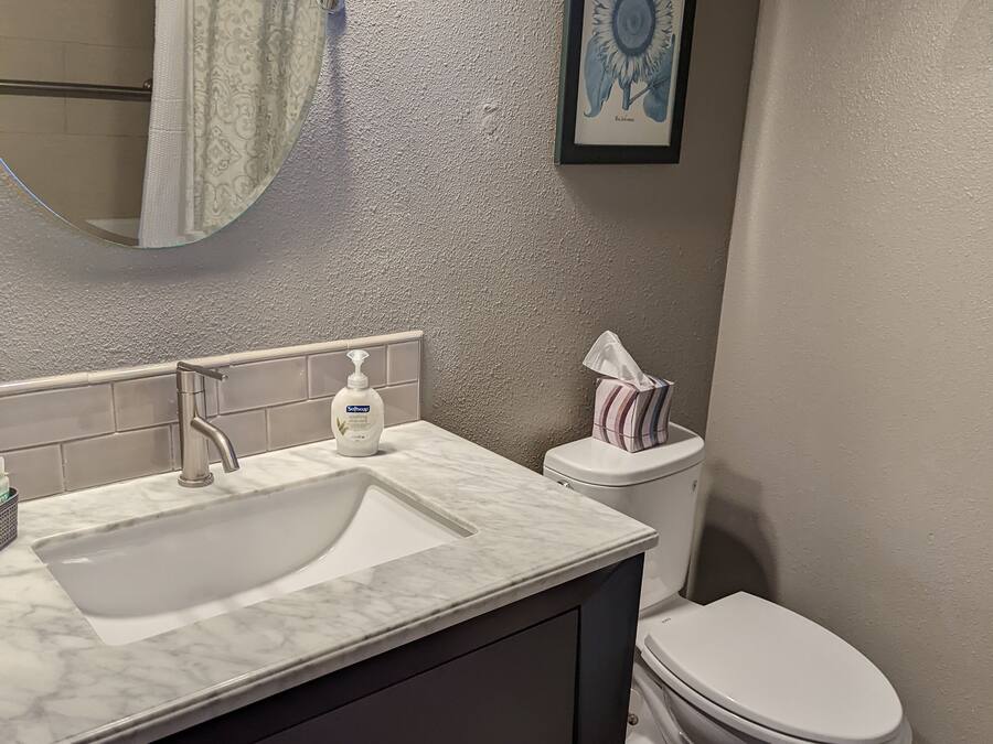 A bathroom with a white sink, dark vanity, and a toilet.