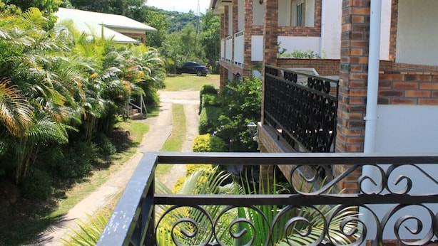 A residential area with a brick house, a paved pathway, and lush greenery. - La Rivière St Louis, 2-room apartment "Furnished tourist accommodation 3 *** (Le Ouaki)