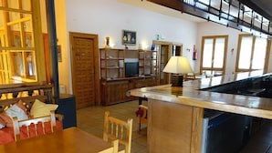 A cozy kitchen with a wooden dining table, chairs, and a small island with a sink.