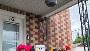 En balkon med plantekasse, blomsterkasser og et nummer 52 på væggen.