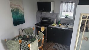 Et kompakt køkken med spiseplads, en mikrobølgeovn, komfur og vask.