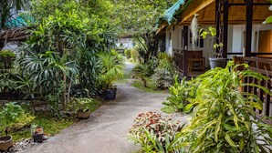 Un sendero que lleva a una casa rodeada de exuberante vegetación tropical.