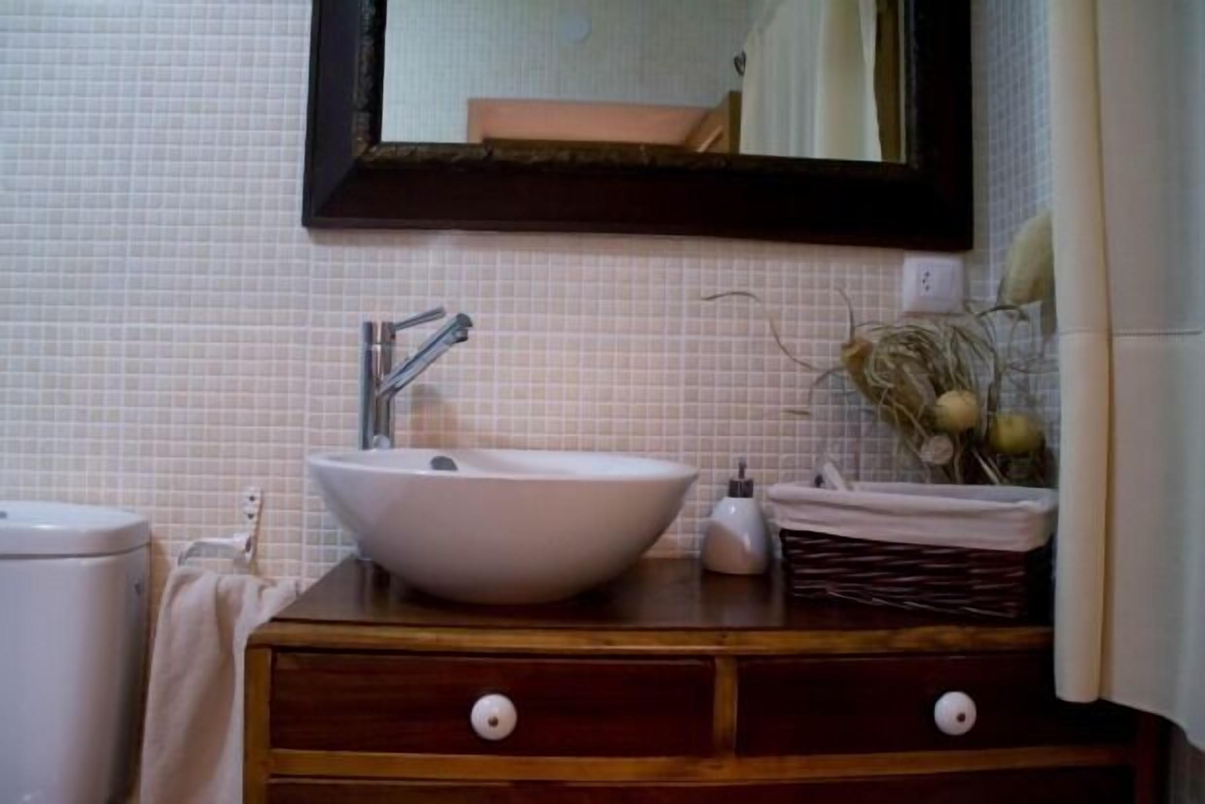 A bathroom with a white sink, a mirror, and a wooden vanity with two drawers.