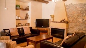 A living room with a fireplace, a television, and a sofa. - Self catering Cal Cabrer for 12 people (Sant Jaume dels Domenys)