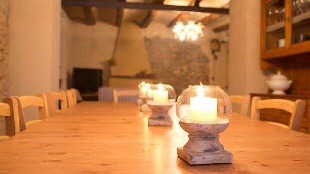A long wooden dining table with candles in glass holders, surrounded by chairs. - Self catering Cal Cabrer for 12 people (Sant Jaume dels Domenys)