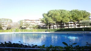 Piscina com superfície de água azul e límpida, rodeada por vegetação exuberante e árvores.