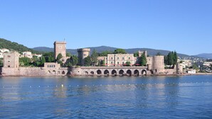 Um castelo histórico com fosso, torres de pedra e uma ponte que leva ao castelo.