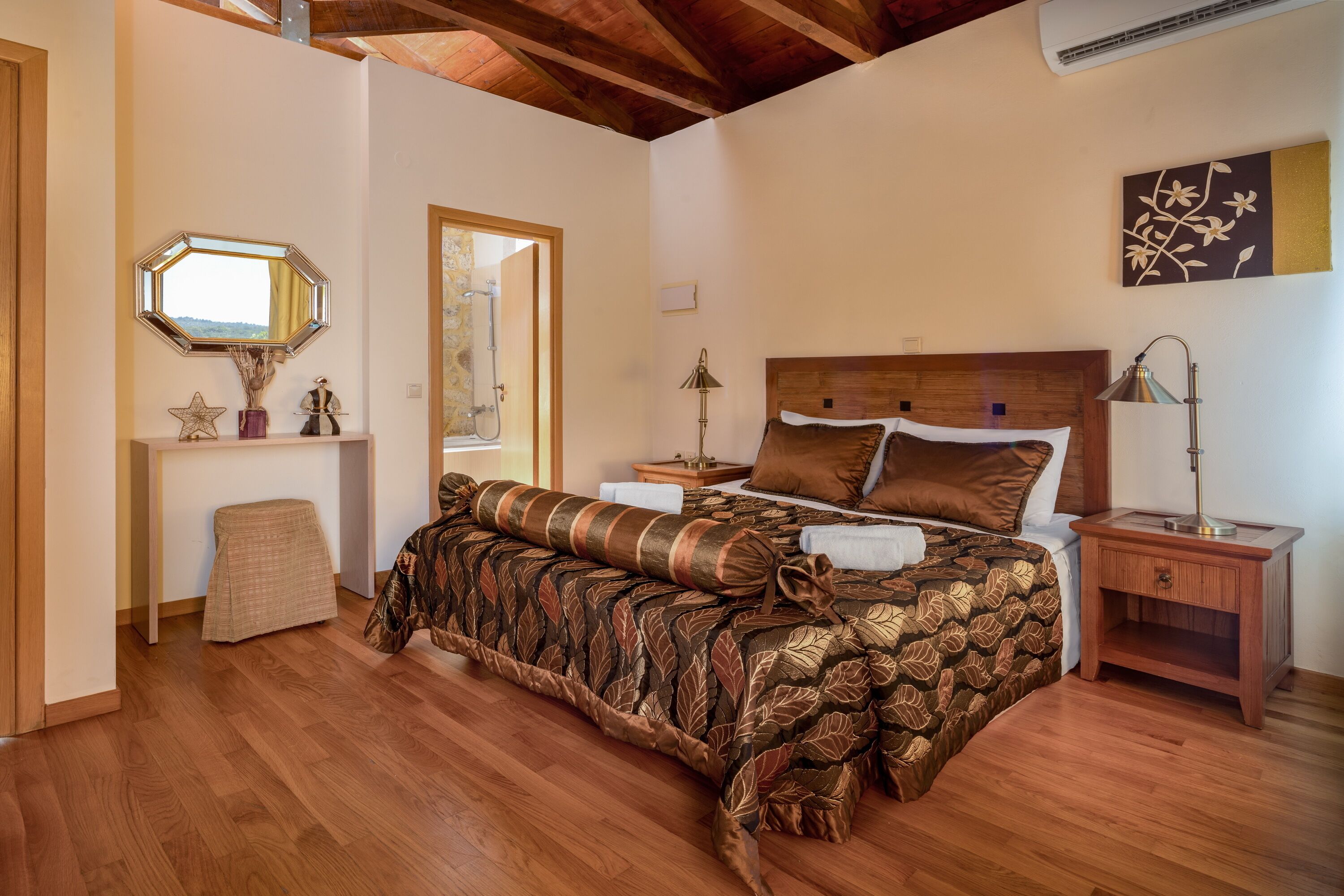 A bedroom with a wooden bed, a nightstand, a bedside table, a mirror, and a wall-mounted artwork.