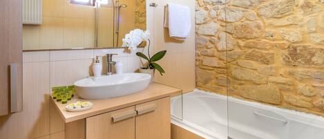A bathroom with a stone wall, a white sink, and a bathtub.