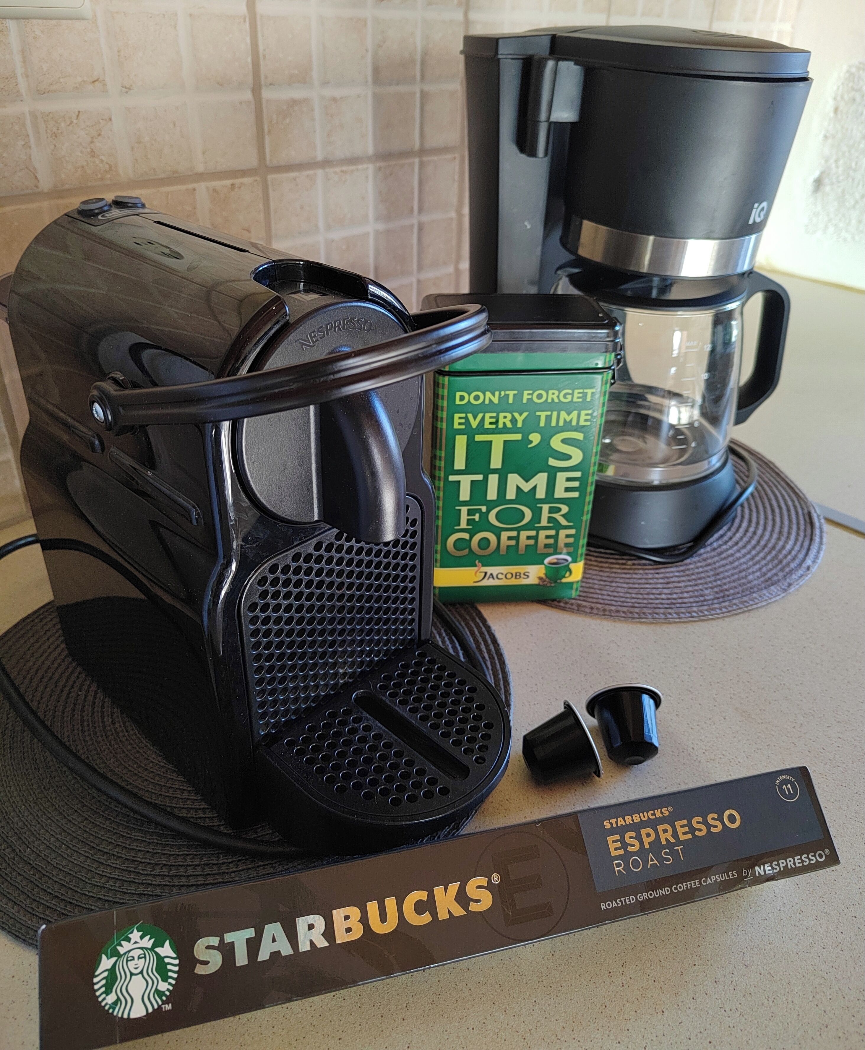 En Nespresso-kaffemaskin, en kaffekapsel och en Starbucks-kaffekapsel på en köksbänk.