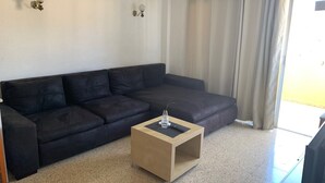 A living room with a dark brown sofa, a small wooden coffee table, and a white air conditioning unit on the wall. - Views of Los Cristianos pier. Pier View. (LOS CRISTIANOS)