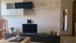 A modern living room with a flat-screen TV, a small table with a plant, and a decorative butterfly on the wall. - Views of Los Cristianos pier. Pier View. (LOS CRISTIANOS)