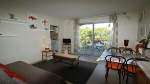 A room with a bed, a desk, a chair, a TV, and a balcony with a table and chairs. - CHARMING STUDIO RESIDENCE SECURE WITH 3 POOLS - LARGE TERRACE + PARKING (Mandelieu-la-Napoule)