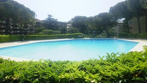 A rectangular swimming pool surrounded by lush greenery and trees, with a clear blue sky above. - CHARMING STUDIO RESIDENCE SECURE WITH 3 POOLS - LARGE TERRACE + PARKING (Mandelieu-la-Napoule)