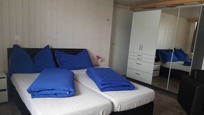 Un dormitorio con cama, armario, espejo y escritorio.
