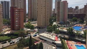 A high-rise residential building with multiple floors, a rooftop pool area, and surrounding greenery.
