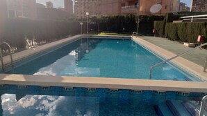 A rectangular swimming pool with a tiled edge and a metal handrail.