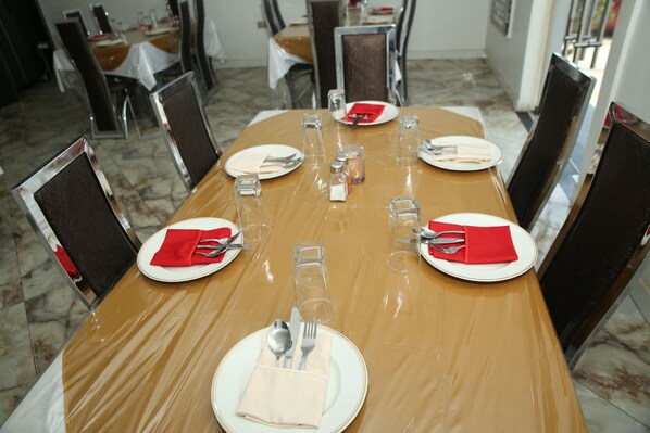 Una mesa de comedor dispuesta con platos, cubiertos y vasos, rodeada de sillas.
