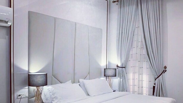 Un dormitorio moderno con una cama grande, lámparas de noche, una mesita de noche y una pequeña mesa redonda.