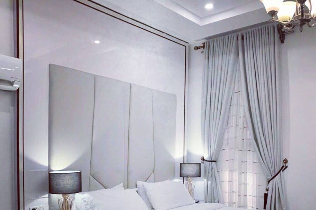Een moderne slaapkamer met een groot bed, bedlampjes, een nachtkastje en een klein rond tafeltje.