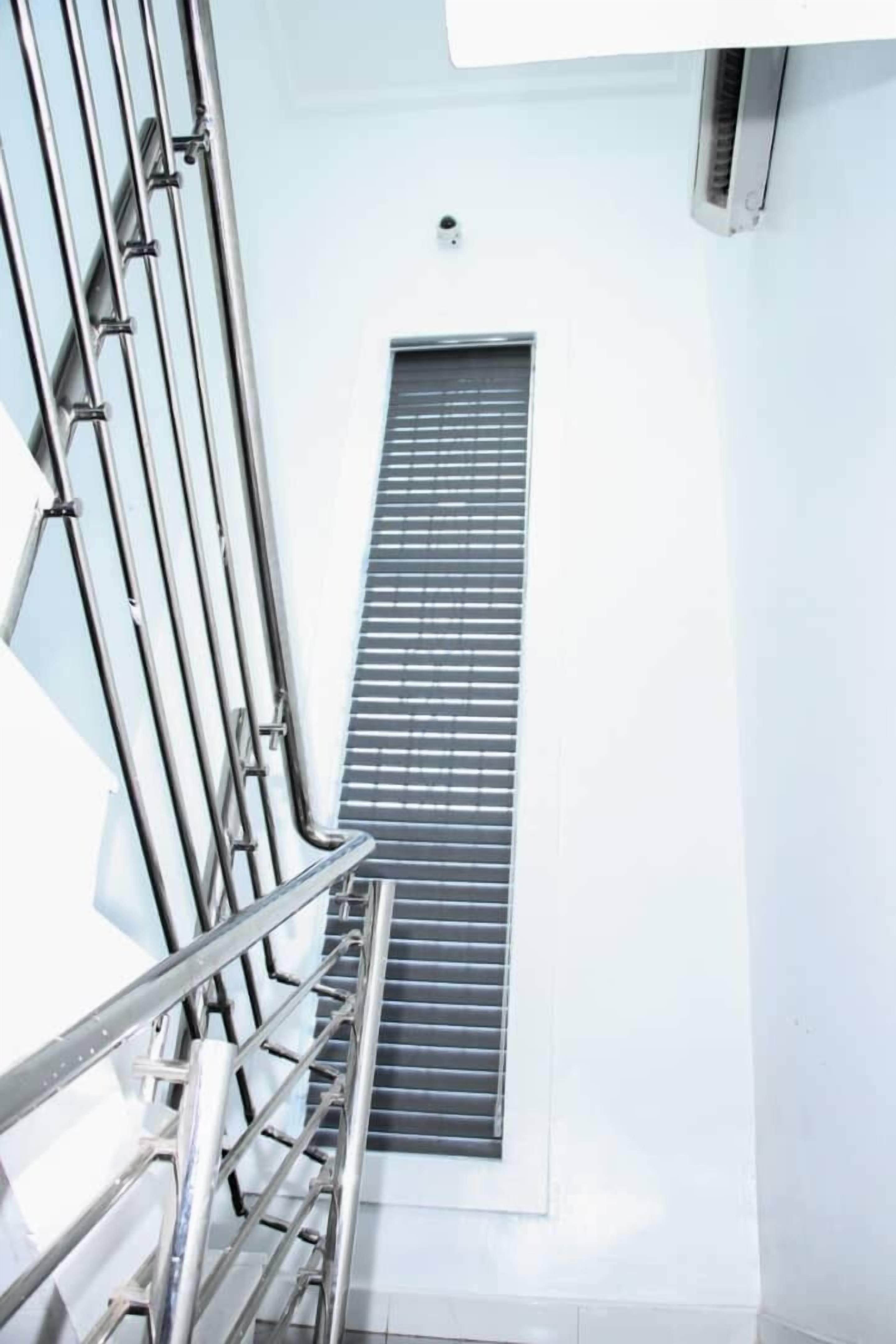 Una escalera con barandillas de metal que conduce a una ventana con persianas horizontales.