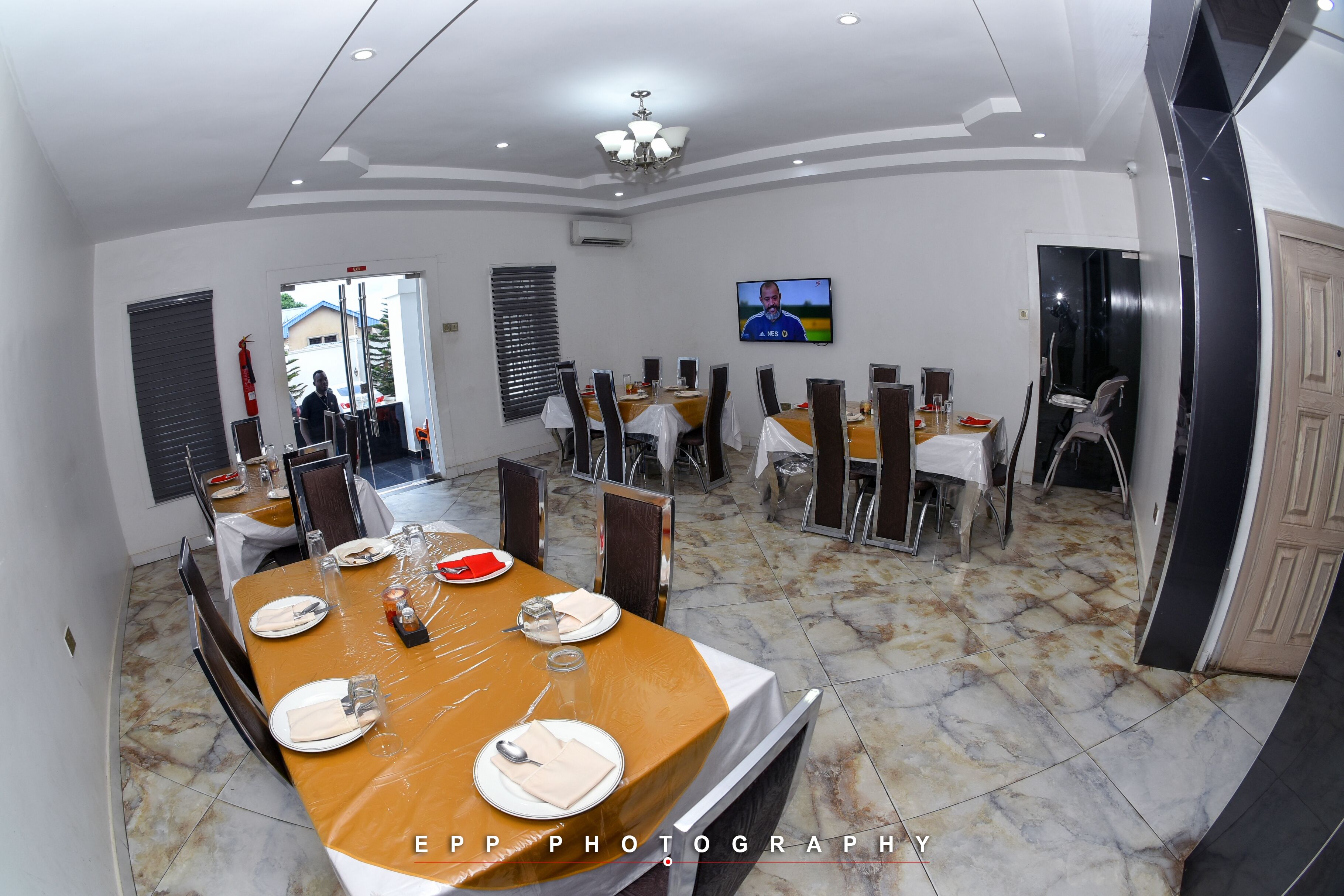 Un comedor con mesas dispuestas para una comida, una pantalla de televisión y un extintor.