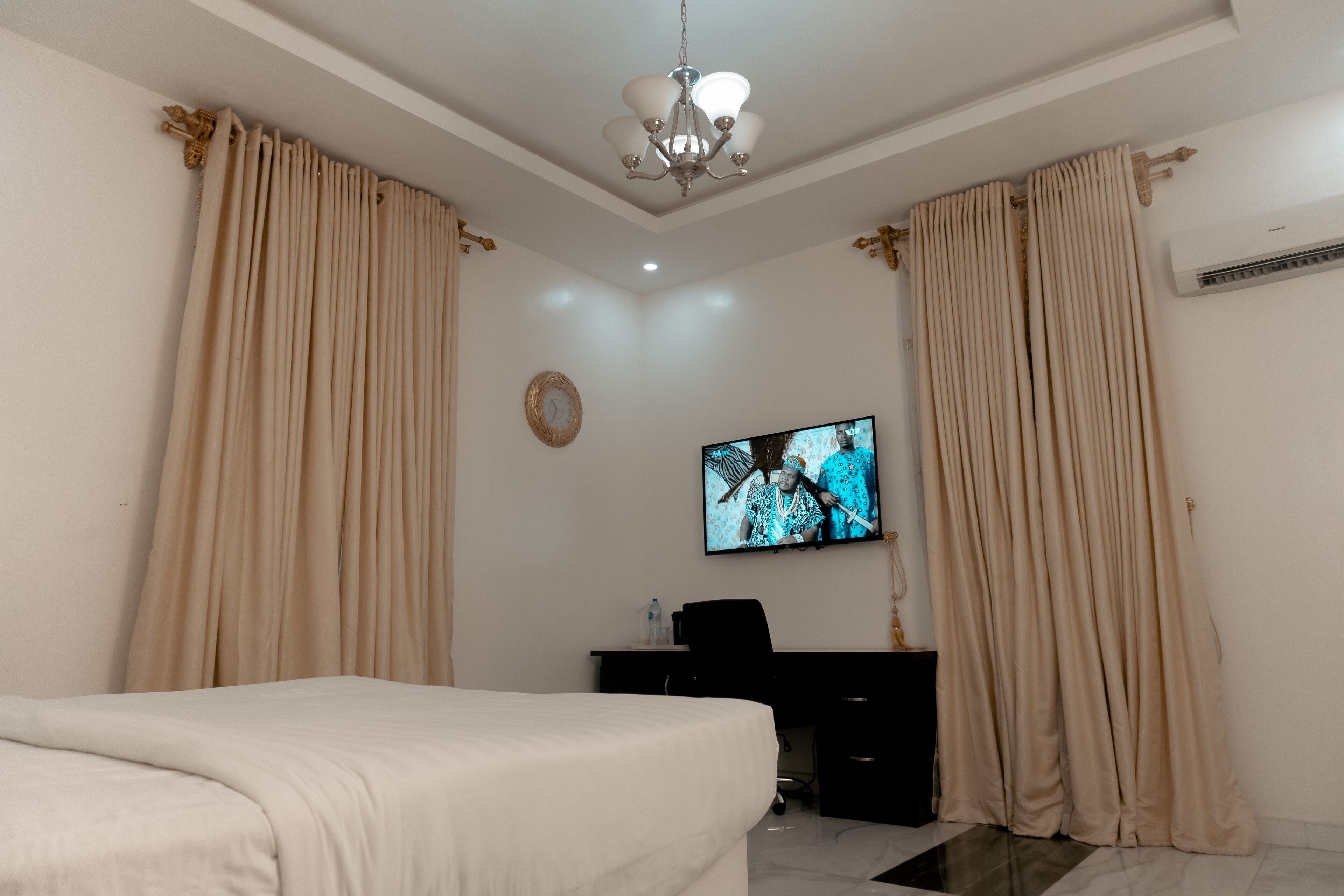 Ein Hotelzimmer mit Bett, Schreibtisch, Fernseher und beigen Vorhängen.