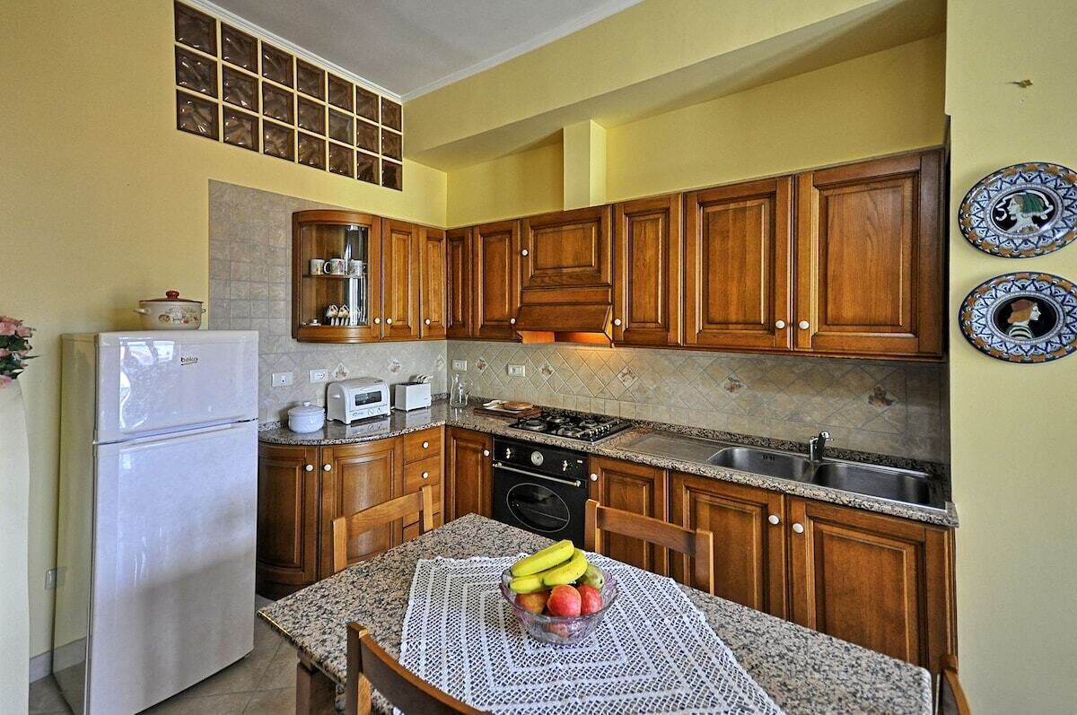 Une cuisine avec des meubles de rangement en bois, un réfrigérateur, une cuisinière et un évier.