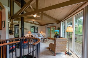 Un salón amplio con chimenea, asientos cómodos y ventanas grandes que ofrecen vistas al exterior.