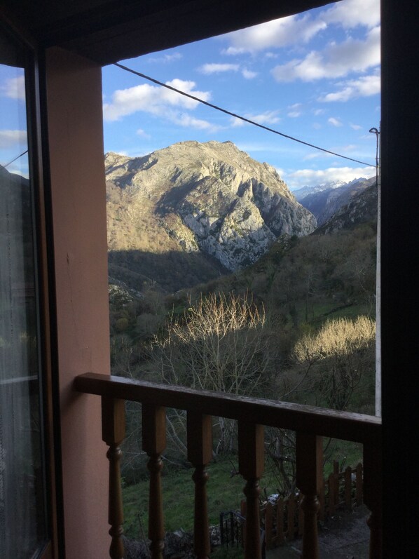 A mountain view from a window with a wooden railing.