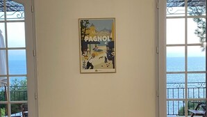 A room with two large windows offering a view of the sea, a poster on the wall, and two blue chairs. - VILLA FACING THE SEA IN CALANQUE COTE BLEUE (Ensuès-la-Redonne)