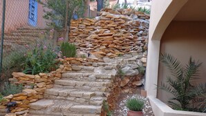 A stone staircase leading up to a building entrance, surrounded by greenery and a potted plant. - VILLA FACING THE SEA IN CALANQUE COTE BLEUE (Ensuès-la-Redonne)