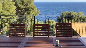 A wooden table and chairs on a balcony with a view of the sea. - VILLA FACING THE SEA IN CALANQUE COTE BLEUE (Ensuès-la-Redonne)