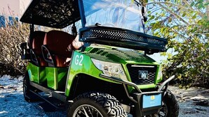 A green golf cart with a raised platform, large off-road tires, and a visible license plate. - AMI Oasis Heated Pool, Spa, Golf Cart, Putting Green, TikiBar, Sundeck (Holmes Beach)