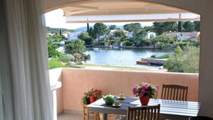A balcony with a table and chairs, overlooking a river and houses.