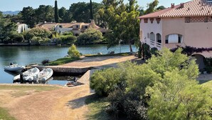 A lakeside property with a dock, boats, and a building with arches.