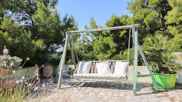 Relax in a charming outdoor setting with a rustic swing set and lush greenery.