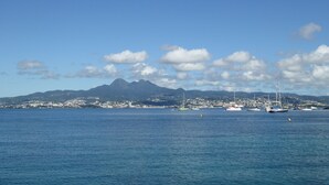 Eine Küstenlandschaft mit Bergen im Hintergrund, ruhigem Meer und mehreren Booten.