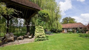 A garden with a gazebo, outdoor seating, and a house with a red-tiled roof.