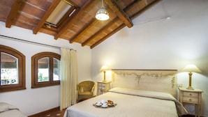 A bedroom with a large bed, two bedside lamps, a chair, and a window with curtains. - Two-room apartment in residence with swimming pool and restaurant (Grosseto)