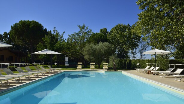 A rectangular swimming pool with white lounge chairs and umbrellas on both sides. - Two-room apartment in residence with swimming pool and restaurant (Grosseto)